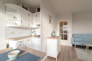 a kitchen with white cabinets and a blue couch at Strandidyll- Wohnung 41 in Grömitz
