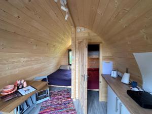a large wooden room with a kitchen in a tiny house at Reservoir View Glamping Pod in Dol-y-gaer Station