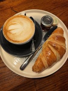 a plate with a cup of coffee and a croissant at The Plume of Feathers in Farnham