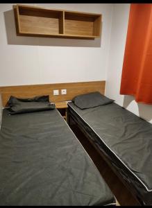 two twin beds in a room with an orange curtain at mobil home in La Celle-sous-Gouzon +3 photos