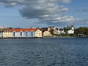 a large body of water with buildings and a windmill at Garden Apartment by the Sea in Sønderborg