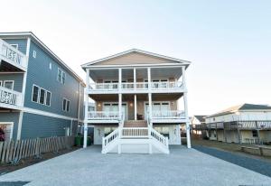 a large apartment building with a white porch and balcony at Burpeau Unit A by Bryant Real Estate in Kure Beach