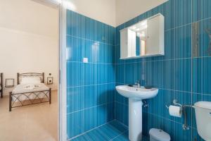 a blue tiled bathroom with a sink and a mirror at Panagis Apartments in Argostoli