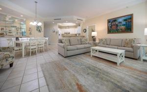 ein Wohnzimmer mit Sofas und einem Tisch sowie eine Küche in der Unterkunft Phoenix on the Bay 1117 condo in Orange Beach