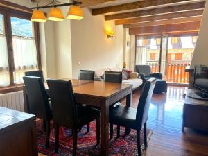una sala da pranzo con tavolo, sedie e divano di Apartament lluminós de muntanya by RURAL D'ÀNEU a Esterri d'Àneu