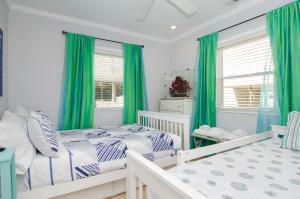 a bedroom with two beds and green curtains at Happy Daze by Bryant Real Estate in Kure Beach