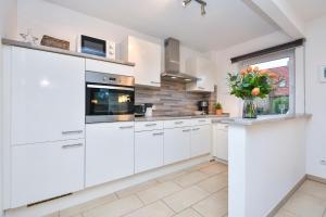 una cocina con armarios blancos y un jarrón de flores en Ferienhaus Bootsmann, en Kellenhusen