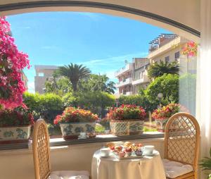 a table with flowers on a window sill with a view at Hotel Sylesia in Letojanni
