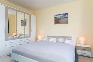 - une chambre blanche avec un lit blanc et deux lampes dans l'établissement Haus Seestern Grömitz Strandglück, à Grömitz