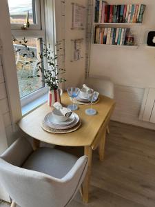 Una mesa de madera con platos y copas de vino encima. en Lama Lodge, en Hawkshead