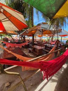 a hammock on a beach with tables and umbrellas at Pousada Barra Mansa in Pitimbu +16 photos