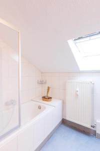 un bagno bianco con vasca e lucernario di - Savanna Lodge Deluxe with Exclusive Design - Apartment 75sqm - Central Location - Terrace with View - Completely Renovated 2024 with Smart TV & Netflix - Separate Kitchen - Free Parking - Near Airport & Train a Duisburg