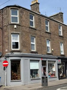 a large brick building with windows on a street at Taylor Close - Spacious Central Ferry Flat in Broughty Ferry