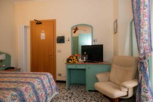 a bedroom with a bed and a desk and a chair at Hotel Magnolia in Albenga
