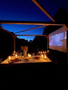 Nowawieś ZbąskaにあるWater Hideout - Floating Villas in Wild Natureの夜にキャンドルと大きなスクリーンが置かれたテーブル