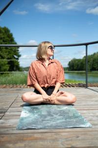 a woman sitting on a pier with her legs crossed at Water Hideout - Floating Villas in Wild Nature in Nowawieś Zbąska