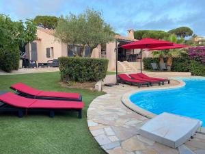 a pool with red lounge chairs next to a house at Vivre Sainte-Maxime à pieds in Sainte-Maxime