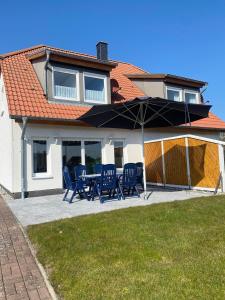 eine Terrasse mit Stühlen und einem Sonnenschirm vor einem Haus in der Unterkunft Haus Paradieskoppel 9223 - Bannesdorf in Niendorf