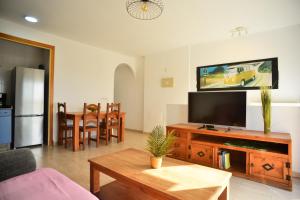 un salon avec une télévision à écran plat et une table dans l'établissement Livingtarifa Apartamento Blue II, à Tarifa
