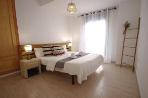 une chambre avec un grand lit blanc avec une fenêtre dans l'établissement Livingtarifa Apartamento Blue II, à Tarifa