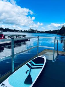 a boat sitting on a dock next to the water at Waterview - Schwimmendes Ferienhaus auf dem Wasser mit Blick zur Havel, inkl Motorboot zur Nutzung in Fürstenberg-Havel