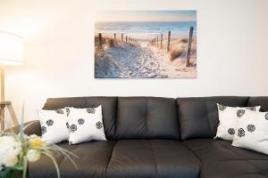 Una sala de estar con un sofá con una imagen de una playa. en Ankerplatz 16, en Neustadt in Holstein