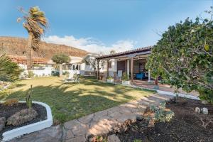 een tuin met een huis met een palmboom bij Villa del Mar Palm Mar in Palm-mar