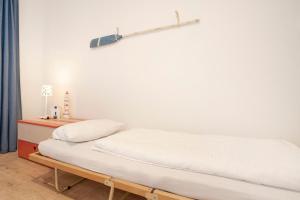 a bed in a room with a white wall at Ankerplatz in Grömitz
