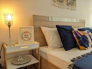 a bed with blue pillows and a night stand with a lamp at Chill Breeze Apartment in Stara Zagora