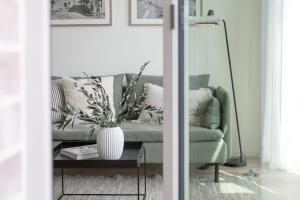 a living room with a green couch and a vase on a table at Eichenhain Saltkrokan in Pelzerhaken