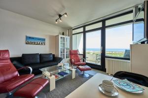 a living room with a black couch and red chairs at Stranddistel 7 Ostseezauber in Burgtiefe auf Fehmarn 