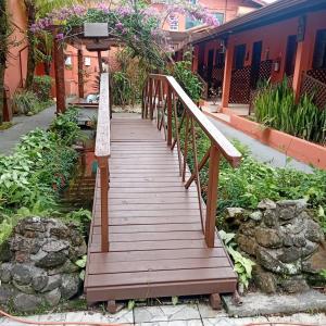 een houten loopbrug in een tuin met een gebouw bij Pousada Gaivotas do Guaraú in Peruíbe