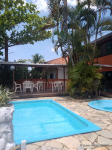 a pool in front of a house with a table and chairs at Pousada Gaivotas do Guaraú in Peruíbe