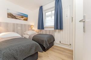 two beds in a small bedroom with blue curtains at Wohnung 113 in Timmendorfer Strand