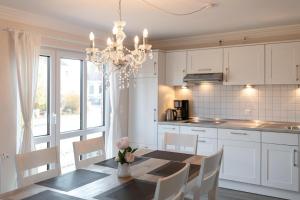 Una cocina con una mesa de comedor y una lámpara de araña. en Lindenstraße 10 Sand & Sonne, en Kellenhusen 33 fotos más