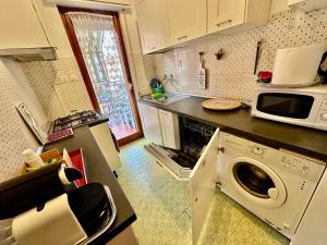 une cuisine avec un lave-linge et un micro-ondes dans l'établissement Penthouse Salus sea view terrace, à Lido di Ostia