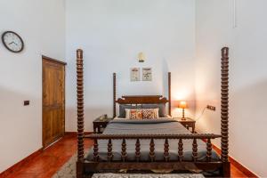 1 dormitorio con cama de madera y reloj en la pared en Sliceinn Somewhere Together In Biligeri, en Madikeri