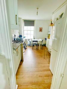 a kitchen with white cabinets and a wooden floor at Shoreditch Rooms Near Tower Bridge in London
