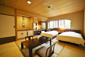 a bedroom with two beds and a table in it at Hotel Kazahaya in Hita
