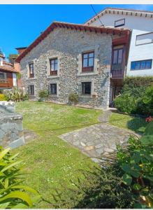 a stone house with a grass yard in front of it at El Resbalón in Comillas