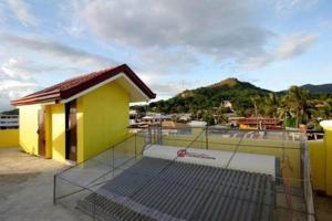 a building with a gate and a mountain in the background at Luis Bay Travellers Lodge Coron in Coron