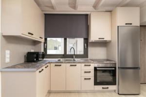 a kitchen with white cabinets and a stainless steel refrigerator at Solmare Loft Suite in Nikiana