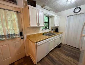 a kitchen with white cabinets and a sink and a window at Kicback Shack - near Forge in Sevierville