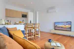 a living room with a blue couch and a kitchen at Penthouse in El Cotillo in Cotillo