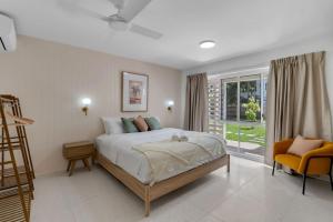 Un dormitorio con una cama y una silla y una ventana. en Tropicana Boutique Hotel - 2, en Cairns North