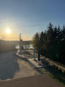 a road with benches and the sun in the distance at Apartamenty Niesiołowice na Kaszubach in Niesiołowice