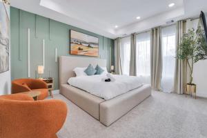 a bedroom with a white bed and two orange chairs at Classy 4BD 3.5BA with Soak Tub Backyard and Game Room in Houston