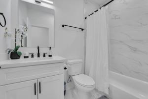 a white bathroom with a toilet and a sink and a shower at Classy 4BD 3.5BA with Soak Tub Backyard and Game Room in Houston