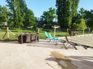 a patio with chairs and tables and a fence at L'étang du griffolet in Ussac