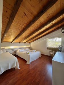 two beds in a room with wooden ceilings at Villa Pantalica lato Sortino in Sortino